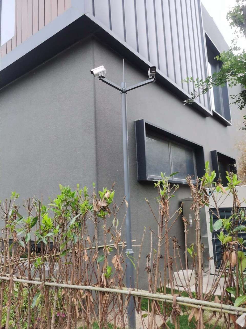 建筑转角的立杆上，两台摄像机朝向不同方向。