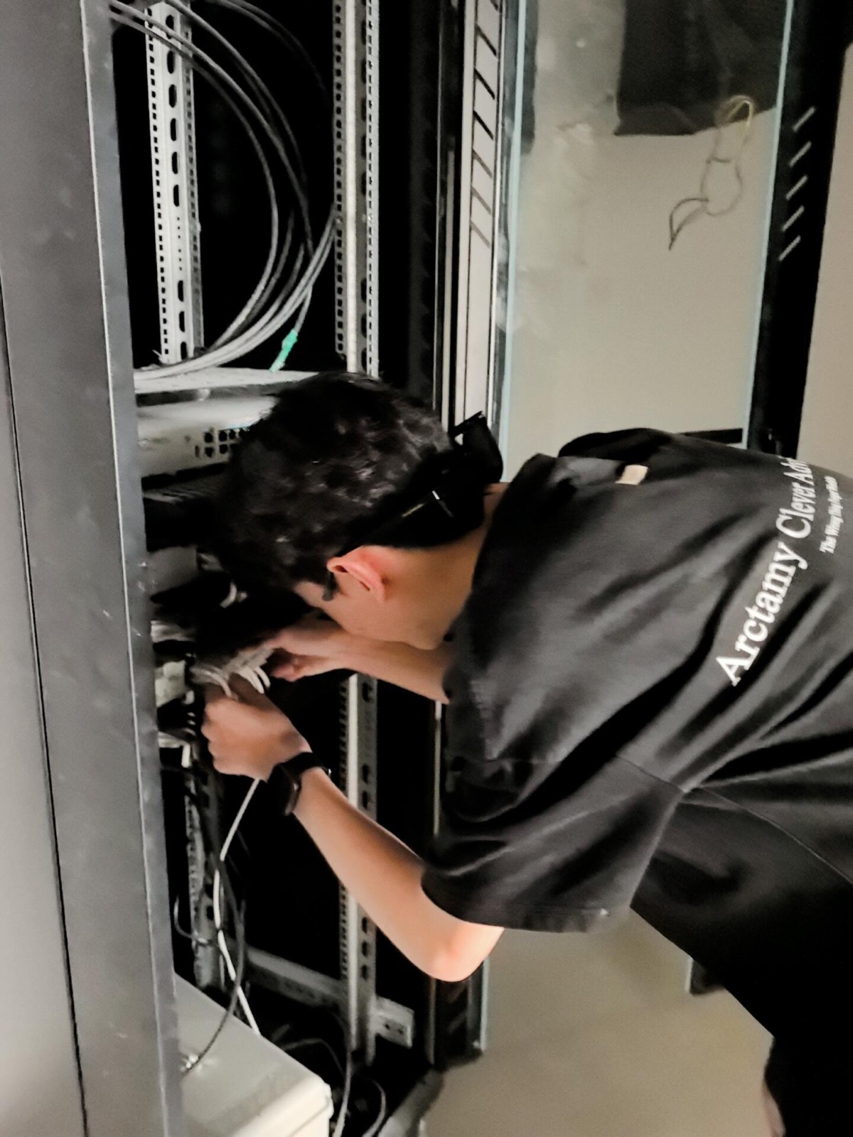 工人俯身整理机柜里的跳线。